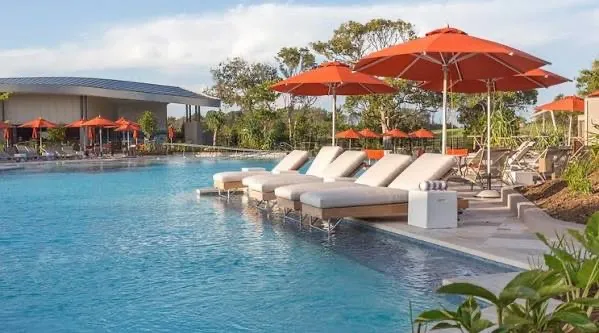 Elements of Byron resort pool with sun loungers, orange umbrellas and subtropical planting, Byron Bay